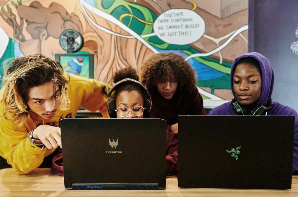 four youths working at computers at Ethos Lab with a colourful mural behind them