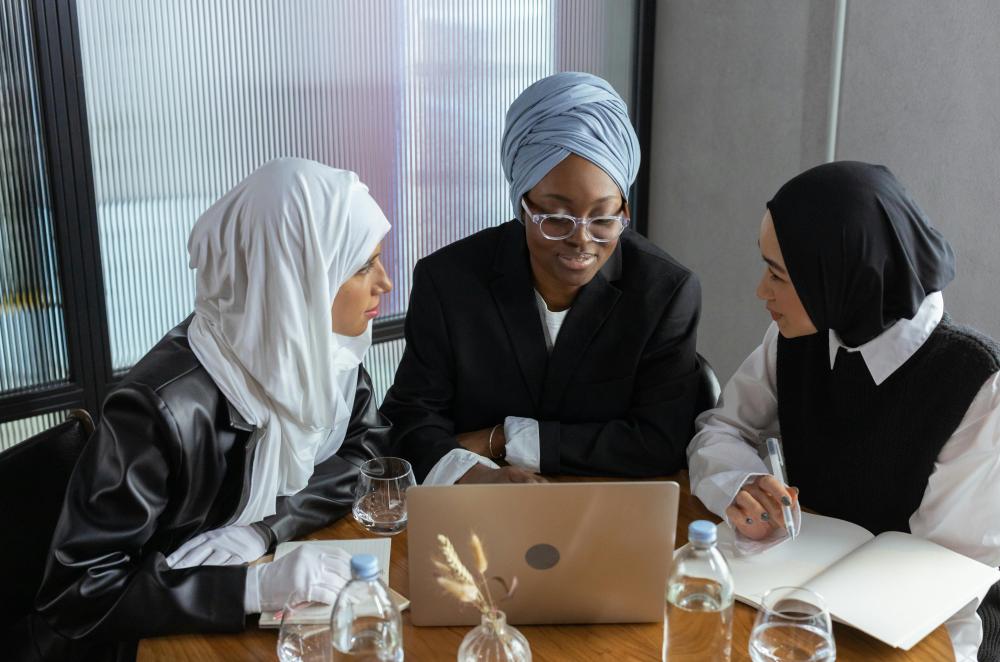 A group of women gathered at a desk, looking at a laptop in a professional office environment