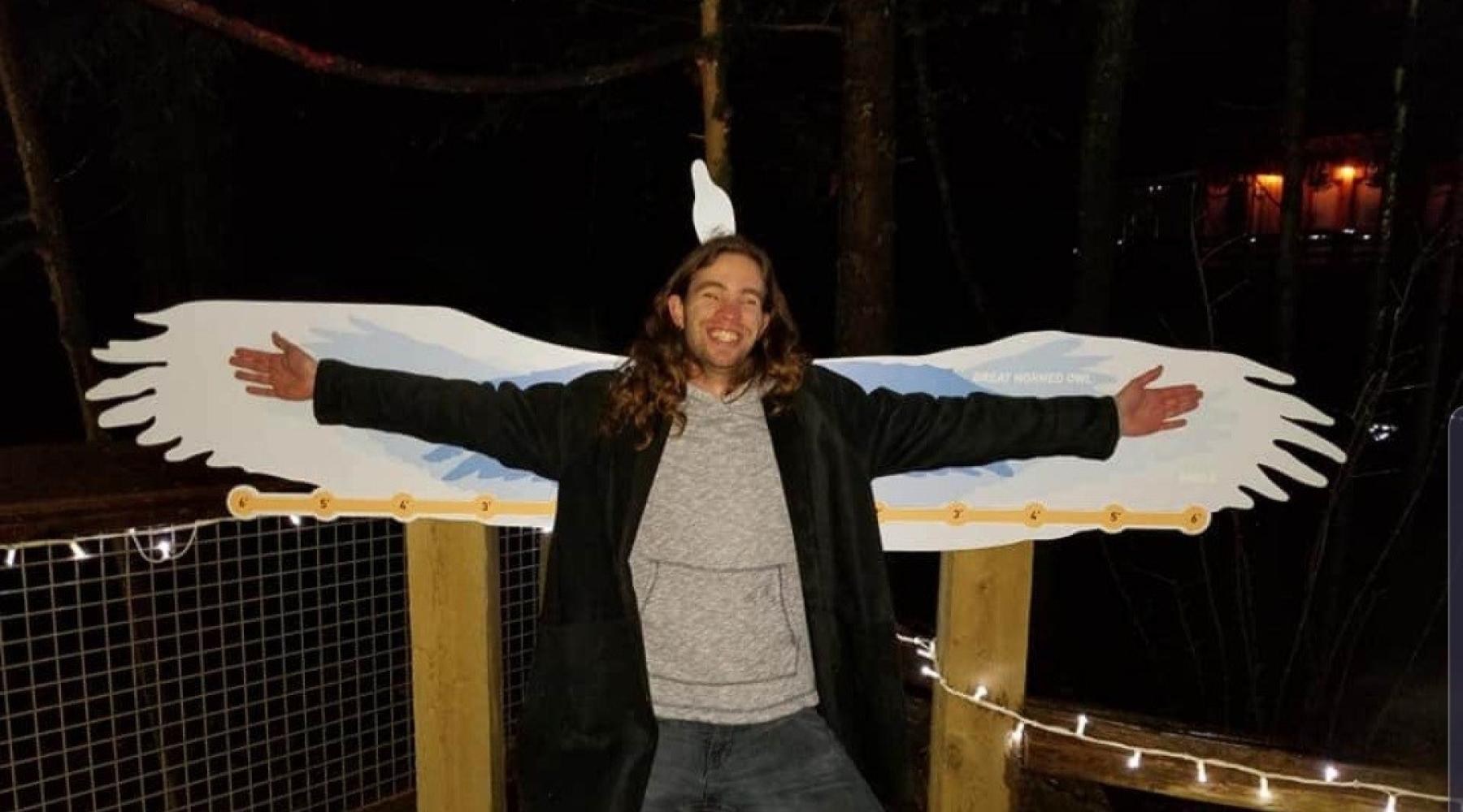 Dylan standing in front of a goose statue with his arms spread